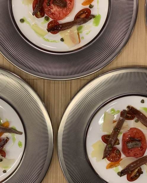 Heirloom tomato with anchovy, capers and aged parmesan on striped chargers, superyacht lunch
