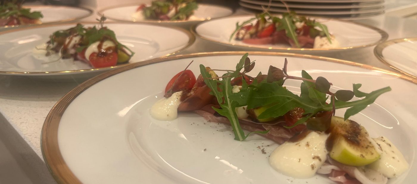 Fresh fig, prosciutto and burrata with rocket and aged balsamic on gold-rimmed china by chef Troy Davidson