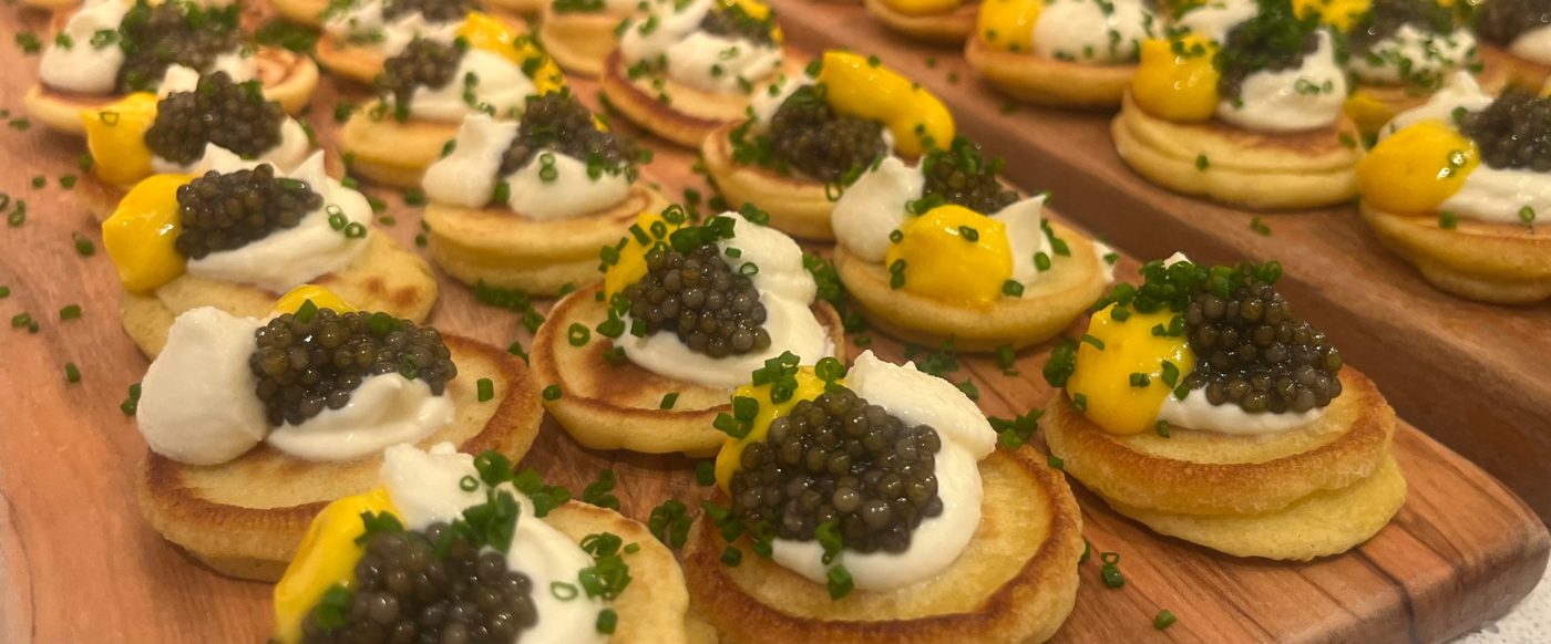 Buckwheat blini with caviar, crème fraîche, egg yolk and chives — superyacht canapé service by chef Troy Davidson